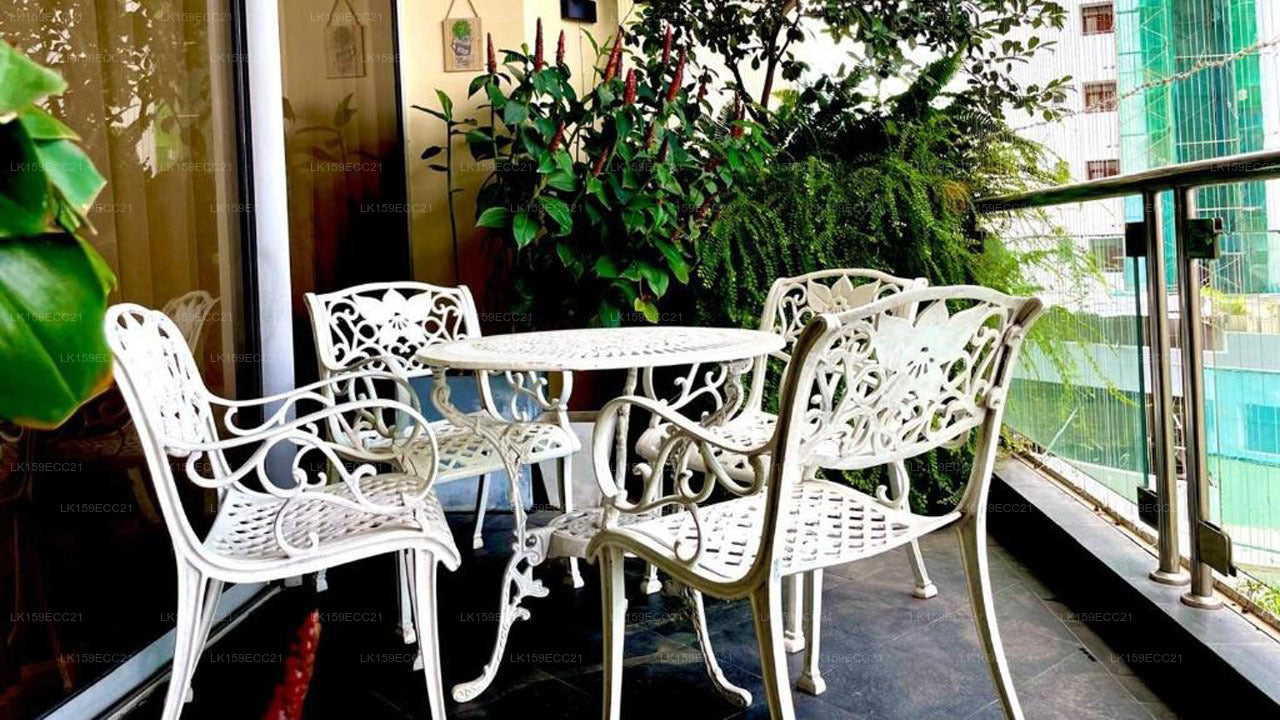 White metal outdoor furniture set on a balcony with plants and cityscape in the background